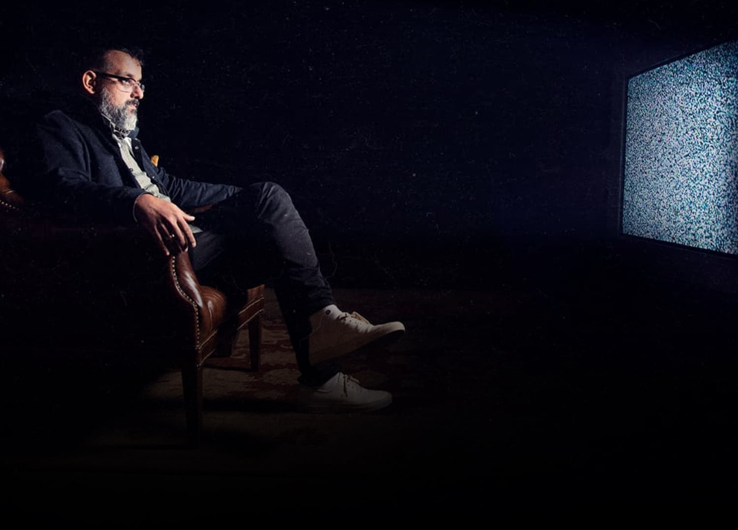 Photo of Suroosh sitting in front of a static filled tv.